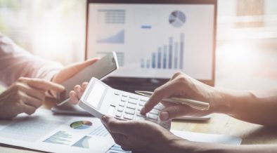 Business and partnership discussing using calculator to review balance sheet annual with holding pen and using laptop computer to calculating budget. audit integrity before investment concept. Premium Photo