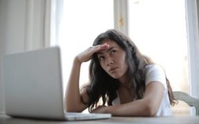 A person sitting at a table with her hand on her head Description automatically generated with low confidence