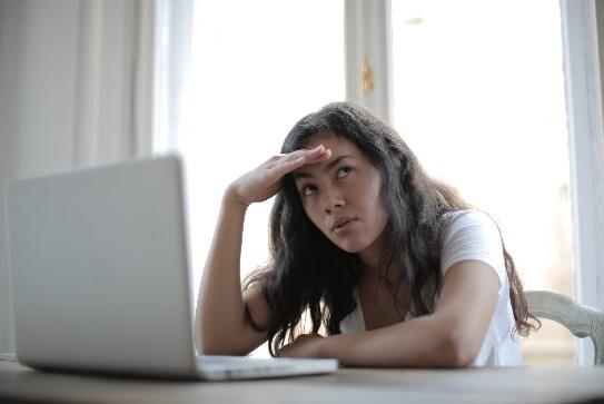 A person sitting at a table with her hand on her head Description automatically generated with low confidence