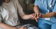A nurse holding a patient's hand Description automatically generated with low confidence
