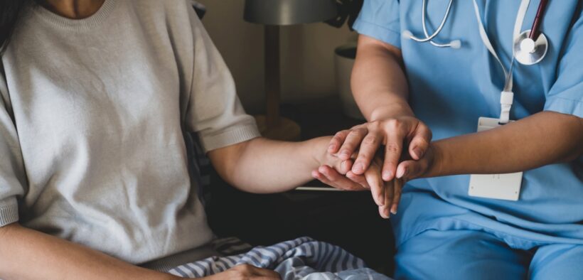 A nurse holding a patient's hand Description automatically generated with low confidence